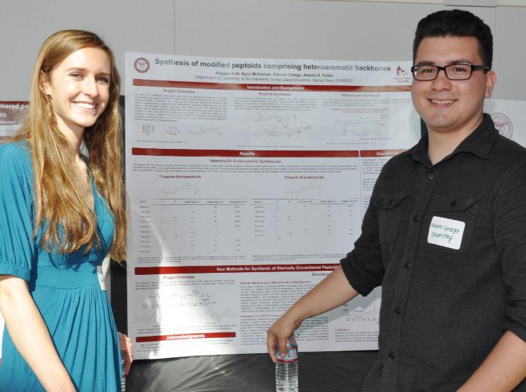 Two students presenting research in front of a poster. image link to story