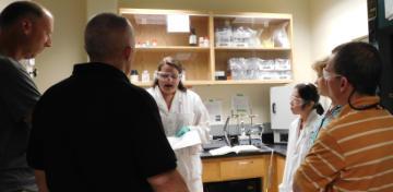 A group of people inside a laboratory during an open house event.