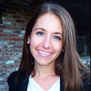 A person smiling in front of a brick wall. image link to story