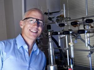 A person smiling in front of scientific equipment.