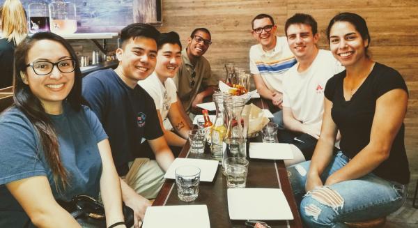 Group of people seated at a restaurant table during a lab outing. image link to story