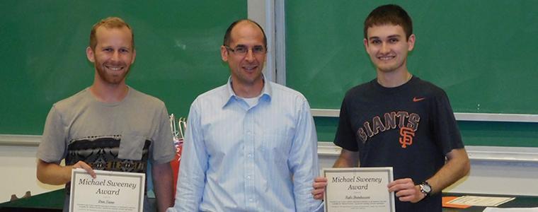 Three people holding certificates in front of a chalkboard. image link to story