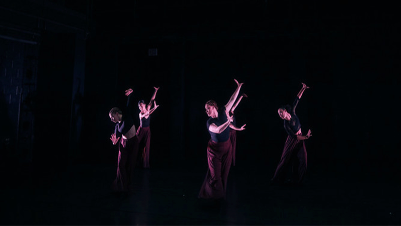 5 female dancers in black tops and maroon pants 
