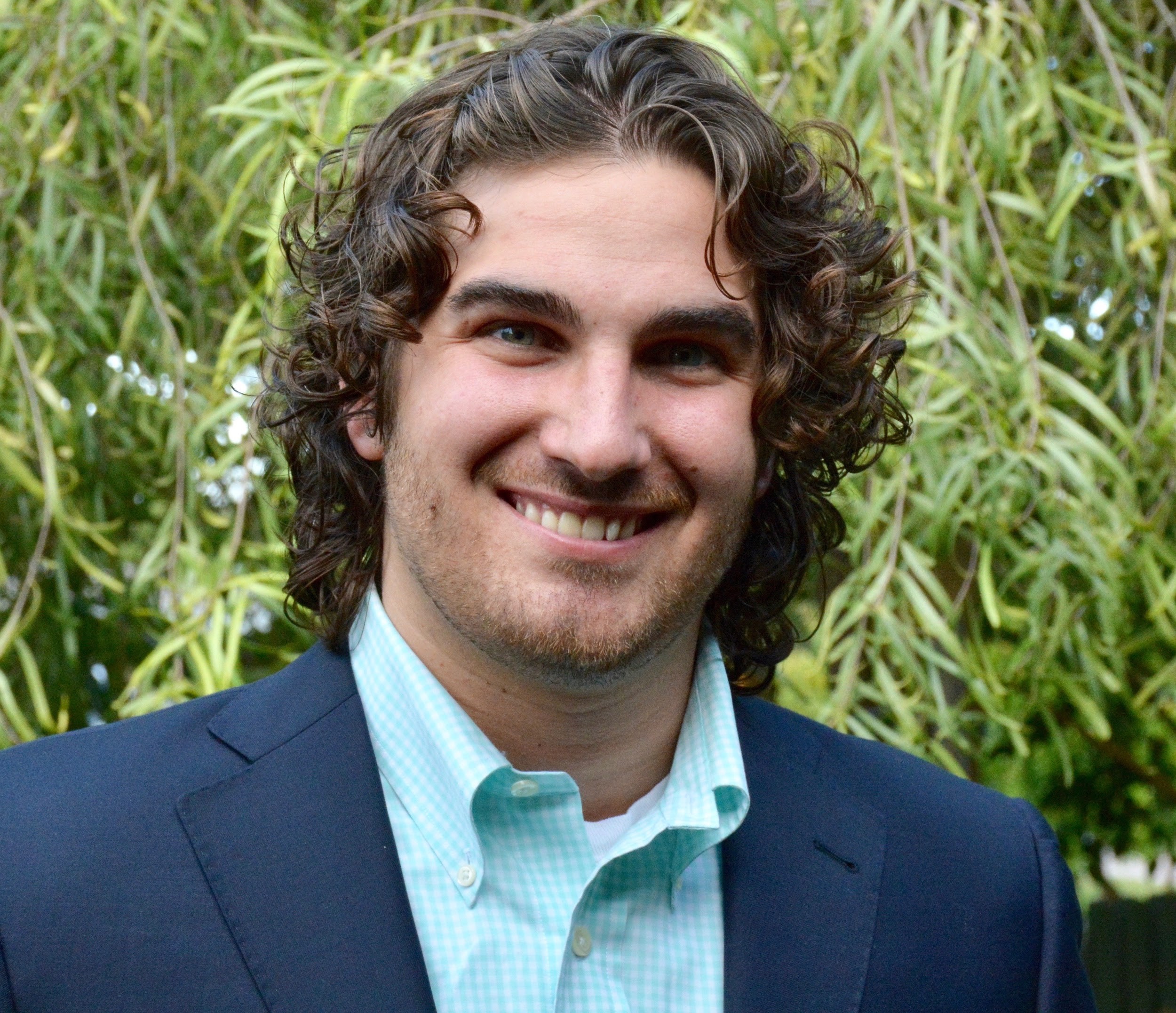 A person smiling in a blue suit and light shirt.