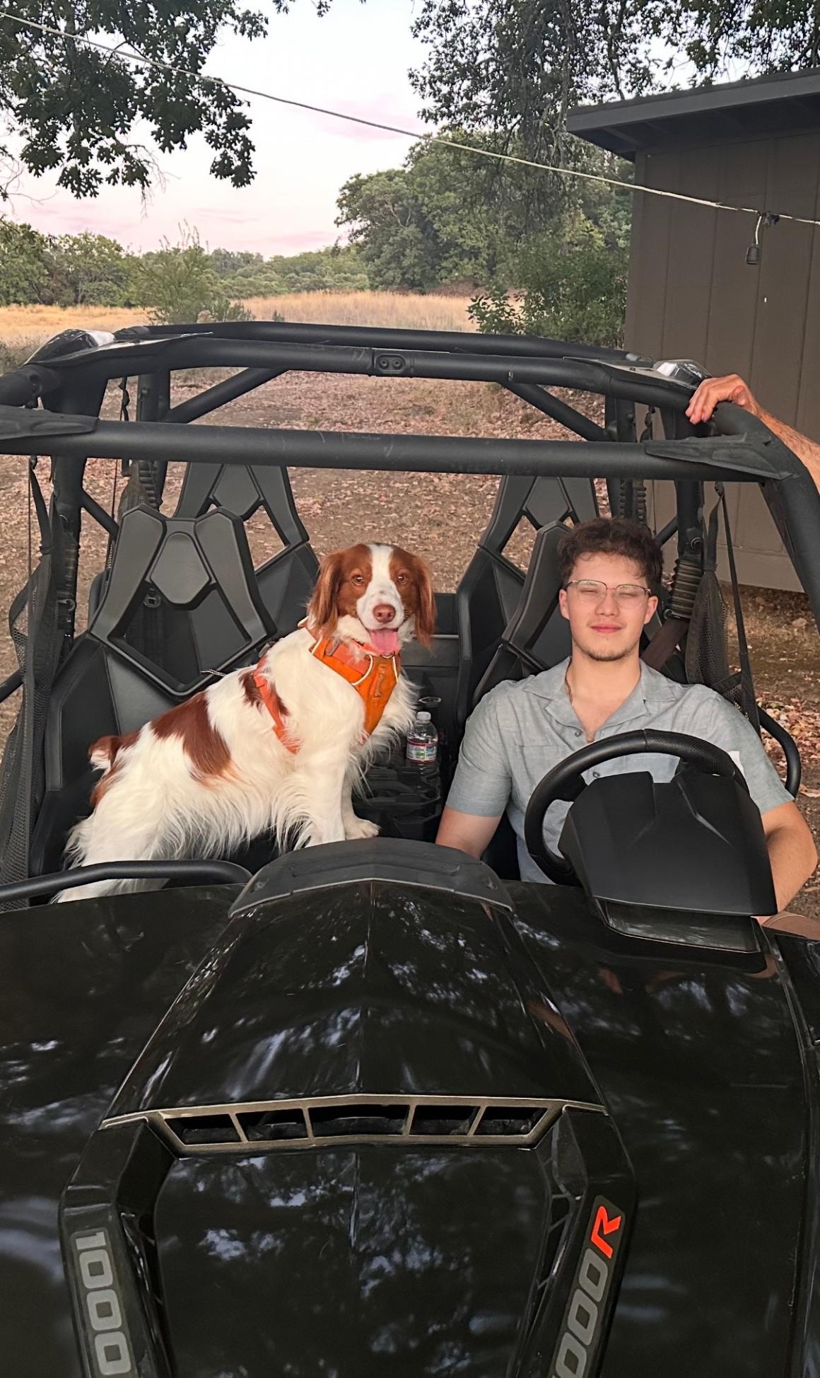 Tyler Pineda at the wheel with his dog in passenger seat. image link to story