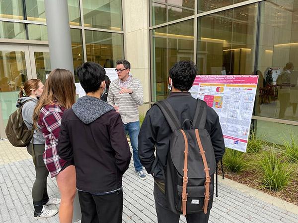 Dr. Ian Carter-O'Connell sharing poster board in front of students