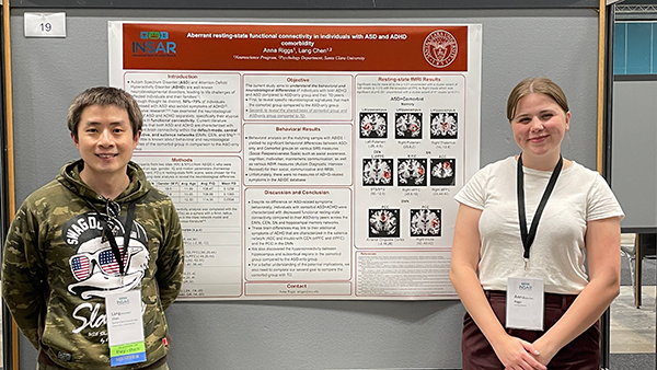 Lang Chen and Anna Riggs standing next to their research poster.