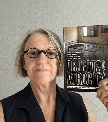 Renee Billingslea holding a book titled Objects of Atrocity: Material Culture and the Challenges of Difficult Histories