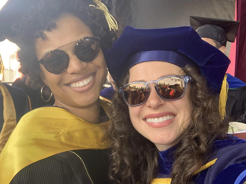 Two faculty members in graduation attire 