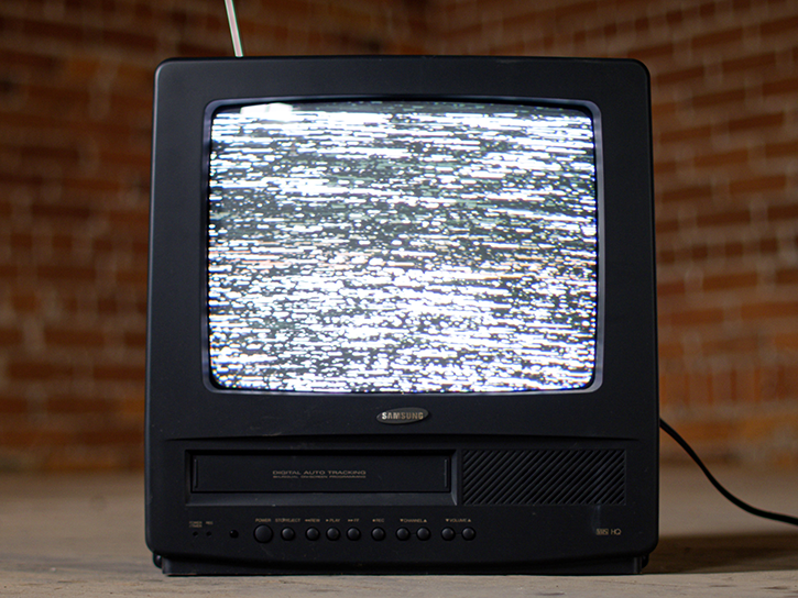 A vintage TB/VHS combo sits in a nondescript brick room with gray static on the TV screen. Photo by Zach Vessels image link to story