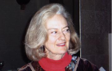 A person wearing glasses and a red top with a dark background. image link to story