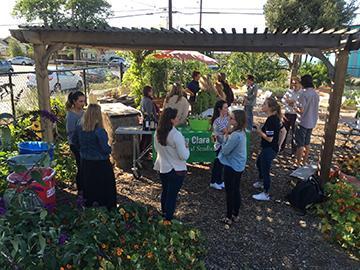 Group of people posing under a wooden structure in a garden.