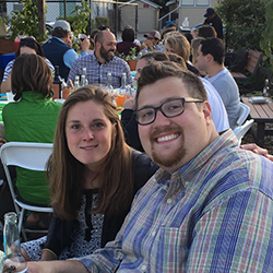 Two people sitting outdoors at an event, smiling.