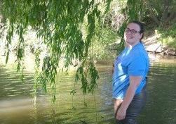 A person standing in a shallow stream, holding a fishing rod. image link to story