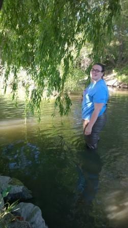 A person standing in a shallow stream, holding a fishing rod. image link to story