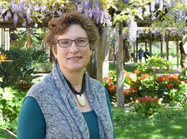 A person standing outside with trees and flowers in the background. image link to story
