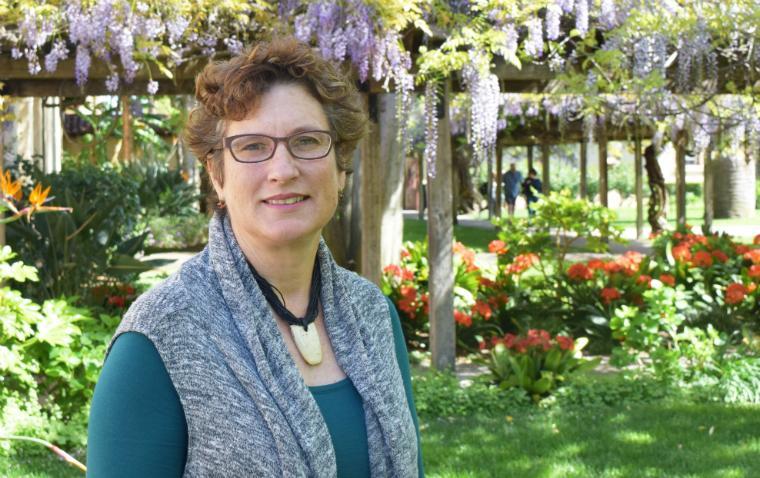 A person standing outside with trees and flowers in the background. image link to story