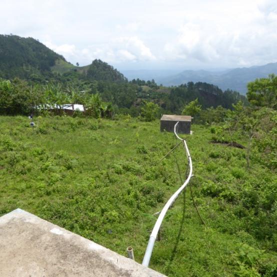 View of lush green hills with irrigation pipes connecting to houses