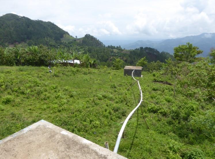 View of lush green hills with irrigation pipes connecting to houses