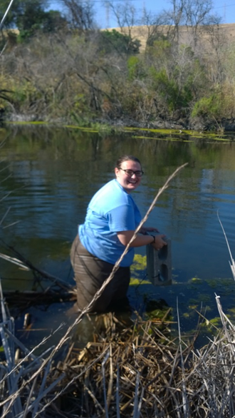 Person in a blue shirt fishing in a pond.