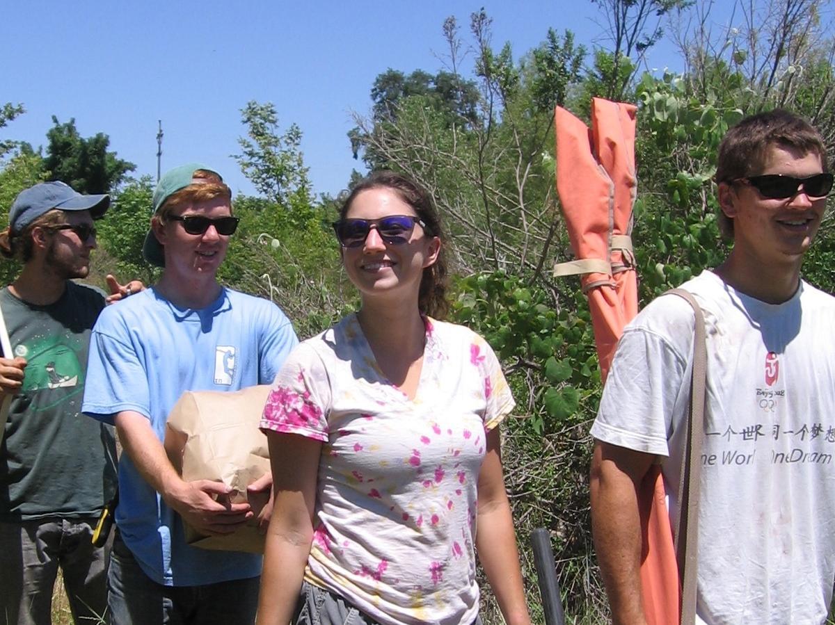 Group of people working outdoors in a green area. 