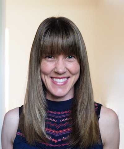 A woman smiling, wearing a sleeveless top with stripes.