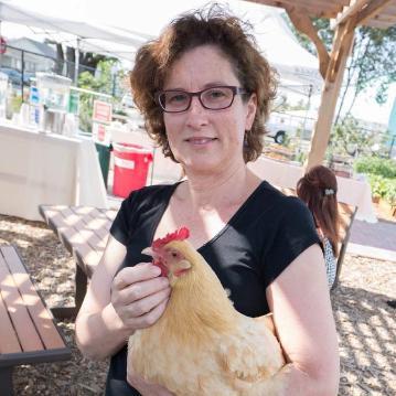 A person holding a chicken at an outdoor market.