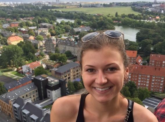 Woman smiling with a scenic view of a town behind her. image link to story