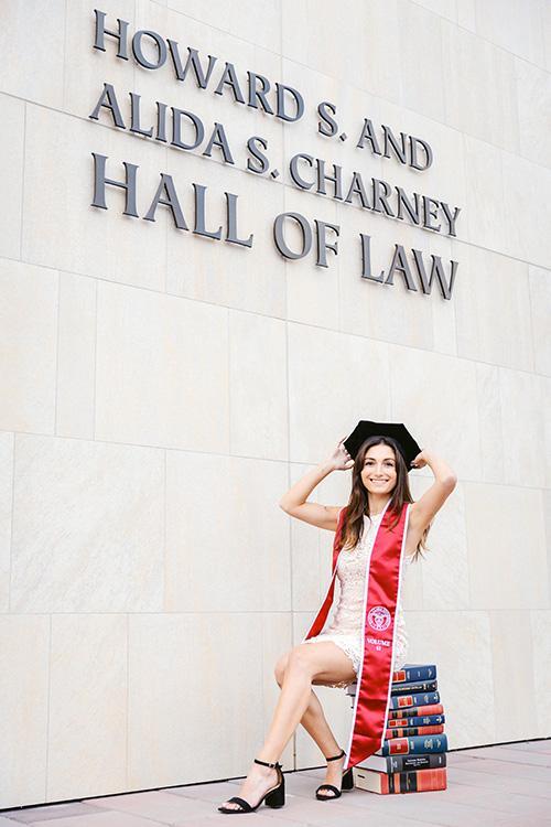 Elia Kazemi in graduation attire in front of Hall of Law sign