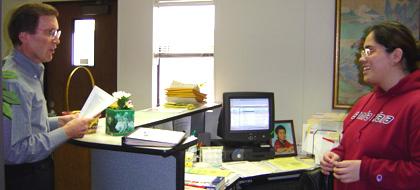 A person at a desk helping another person with papers.