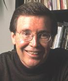 Person smiling in front of a bookshelf.