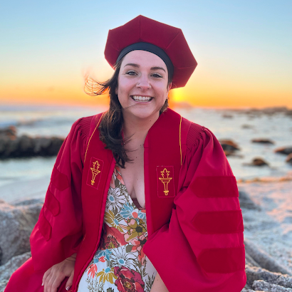 Graduation picture of Michaela Scanlon on a beach at sunset