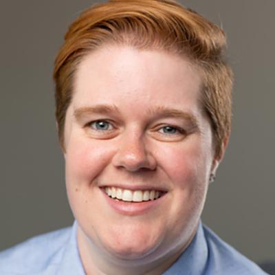 A smiling person in a blue shirt and tie.