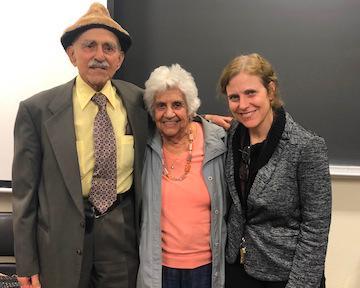 Three individuals standing together, smiling in front of a classroom chalkboard. image link to story