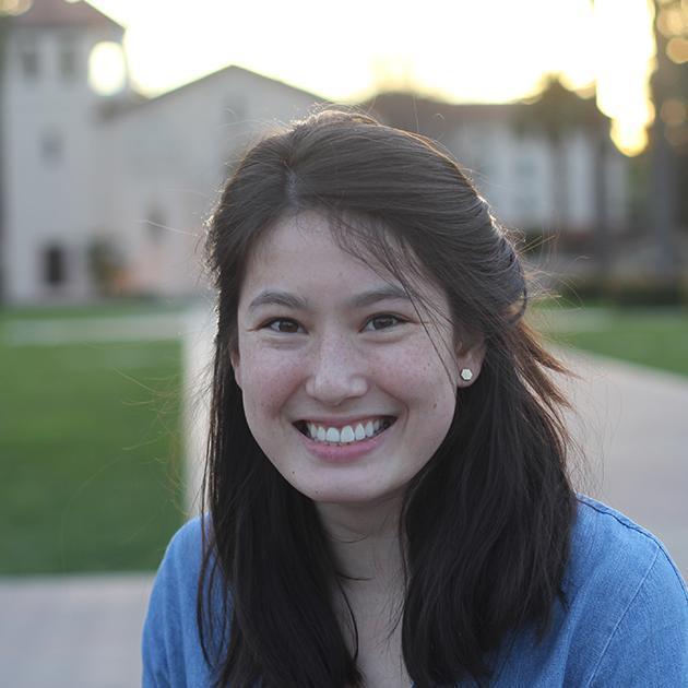 A person smiling outdoors with a building in the background. image link to story