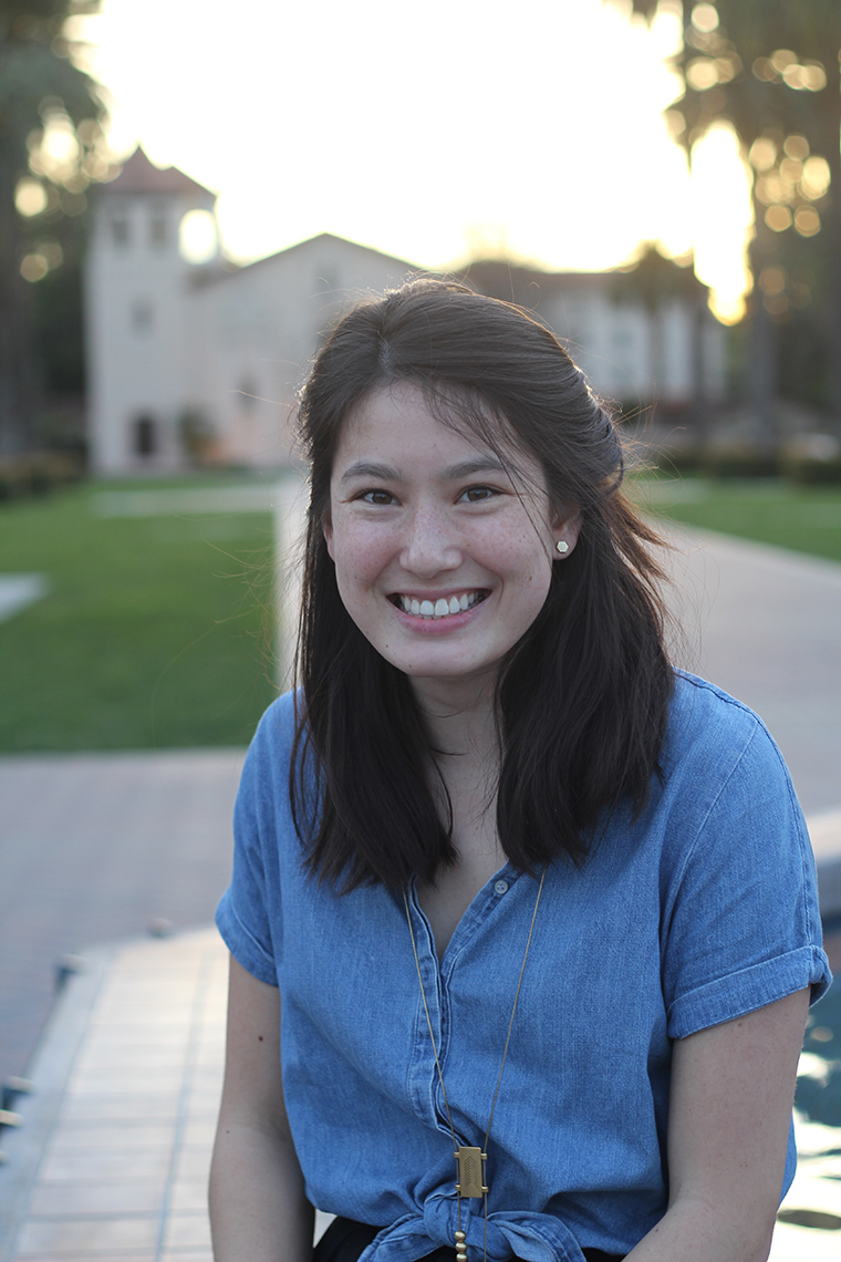 A person smiling outdoors with a building in the background. image link to story