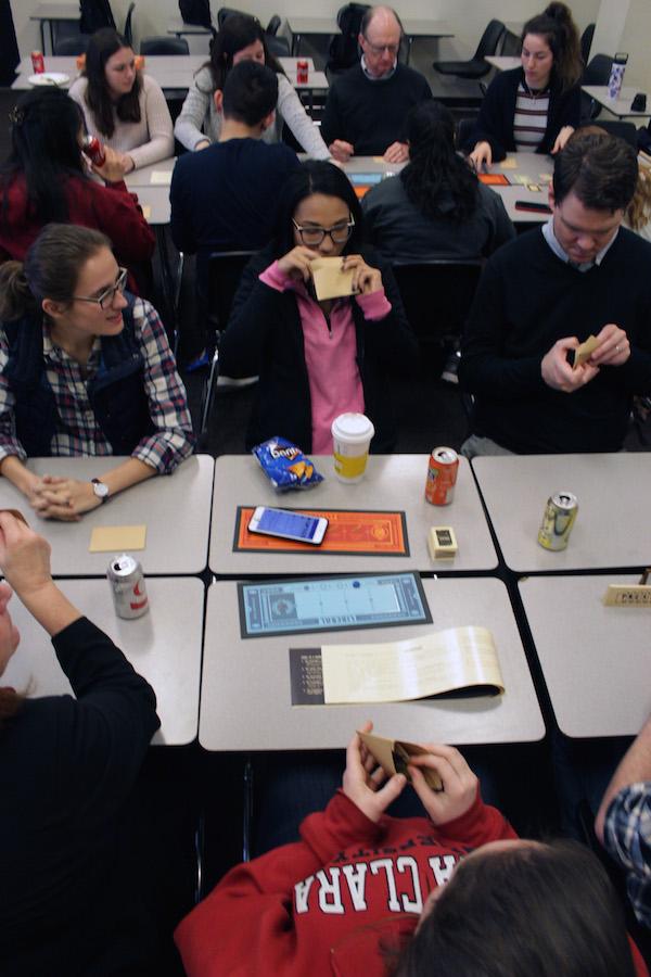 Students playing a board game, Secret Hitler, around a table.