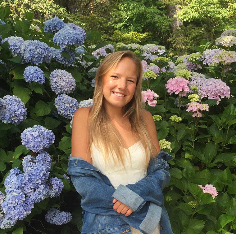 A person in a garden with hydrangea flowers.