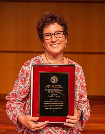 Leslie Grey holding award plaque image link to story