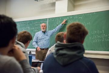 Frank Farris at the chalkboard teaching a classroom of students