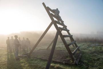 Foggy field with a large wooden A-frame structure in the morning sun. - Link to file