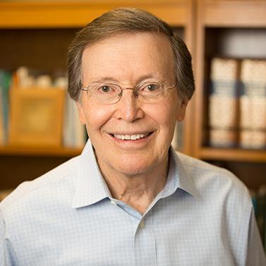 A person smiling in front of bookshelves. image link to story