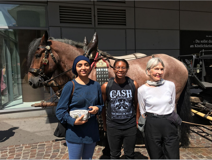 Three people standing in front of a horse and cart in Freiburg. image link to story