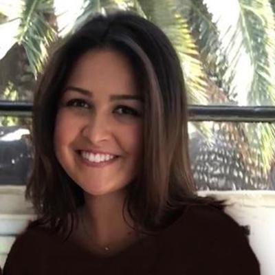 Smiling woman in front of palm trees and railing. image link to story
