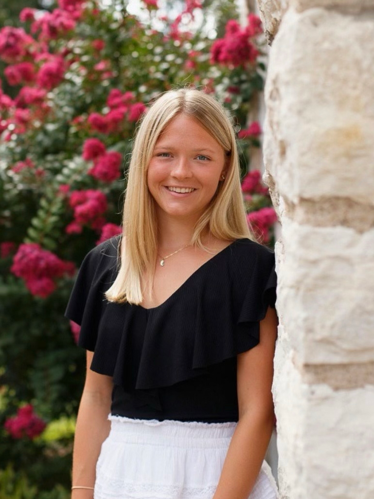 Evelyn Casey standing next to the Adobe wall