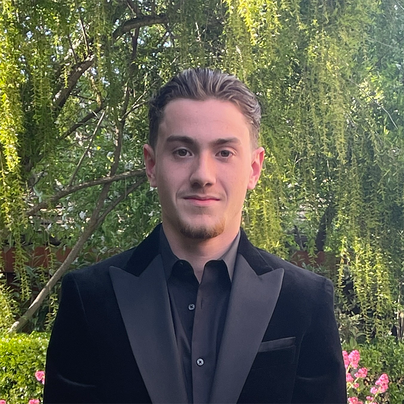 Leonard Cappa headshot outdoors with green trees in background