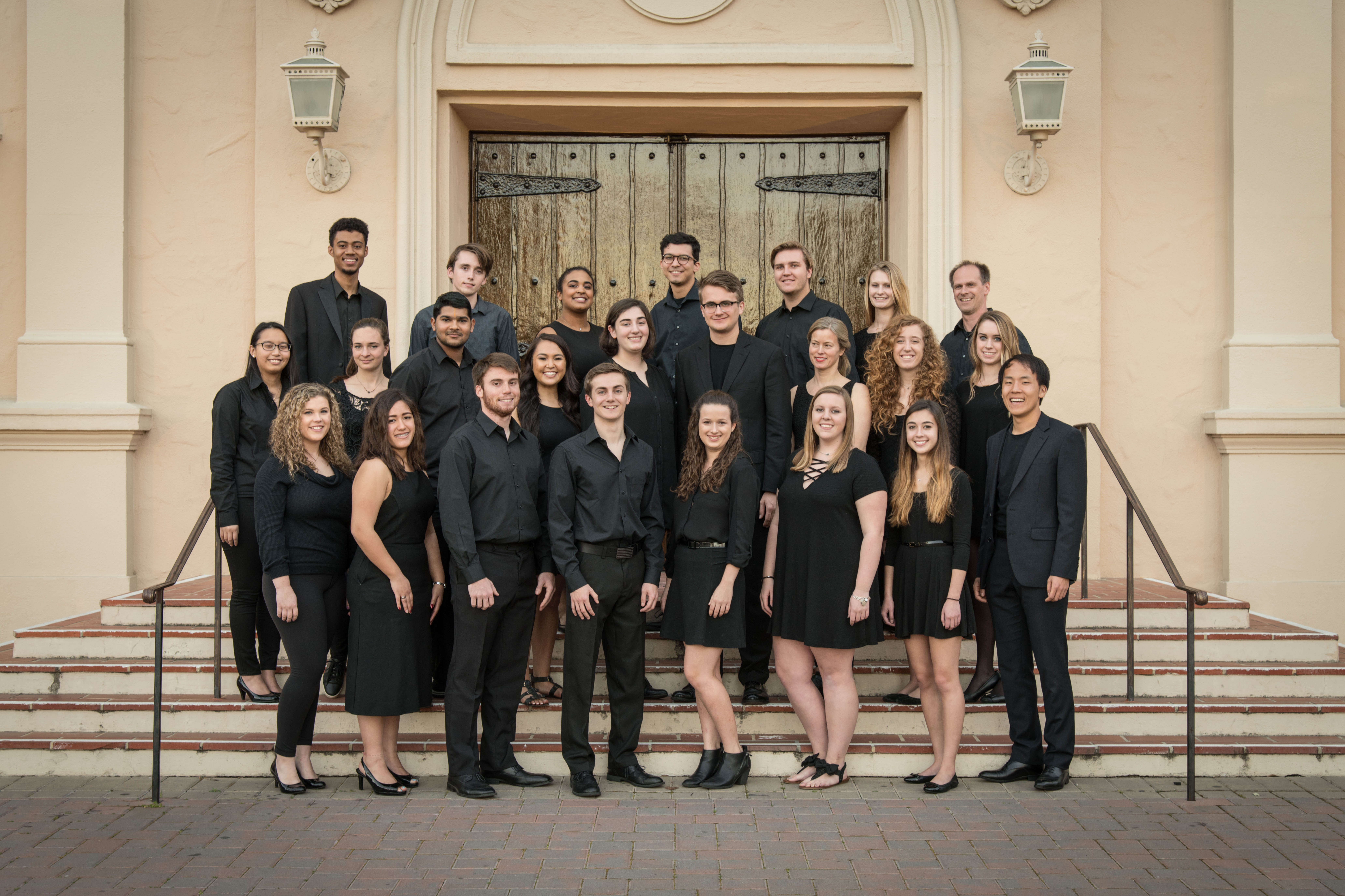 A choir group posing on steps in front of a building.