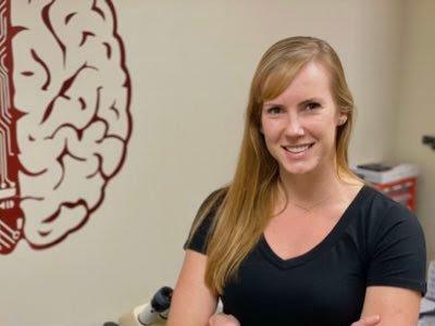 A person standing in an office with a brain diagram on the wall.
