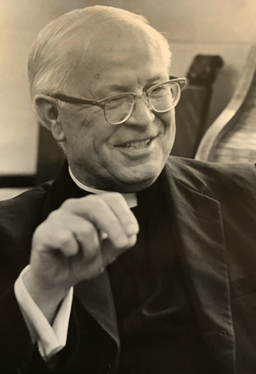 Father Francis L. Markey at desk smiling