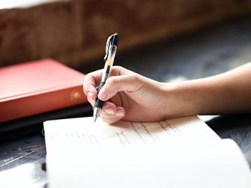 hand holding pen writing in a notebook